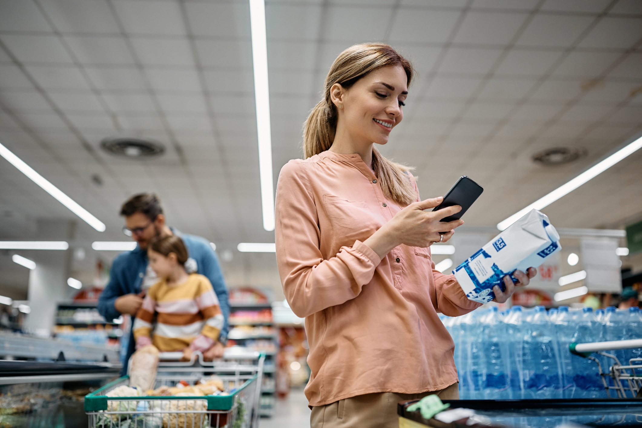 Happy woman scanning QR code on a product while shopping in supermarket.